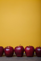 row of apples on a desk 