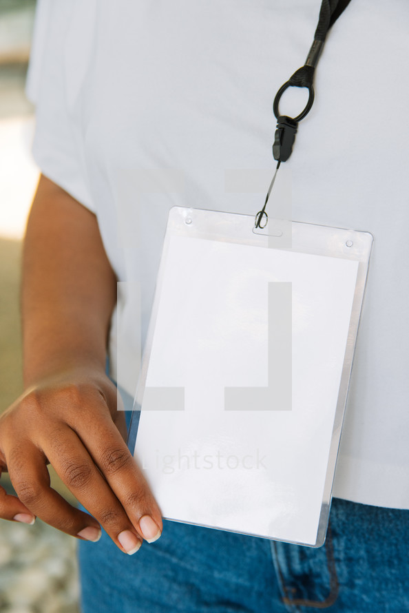 Woman in a white tshirt wearing a large lanyard.