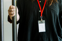 Woman in a black shirt wearing a lanyard while holding a door open.