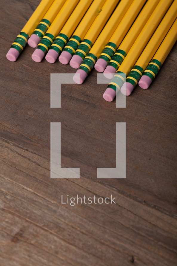 A row of yellow pencils on a wooden surface.