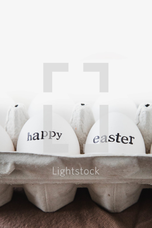 Happy Easter on white chicken eggs in a carton 