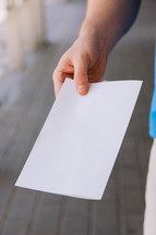 Close up of a man holding out a blank flyer.