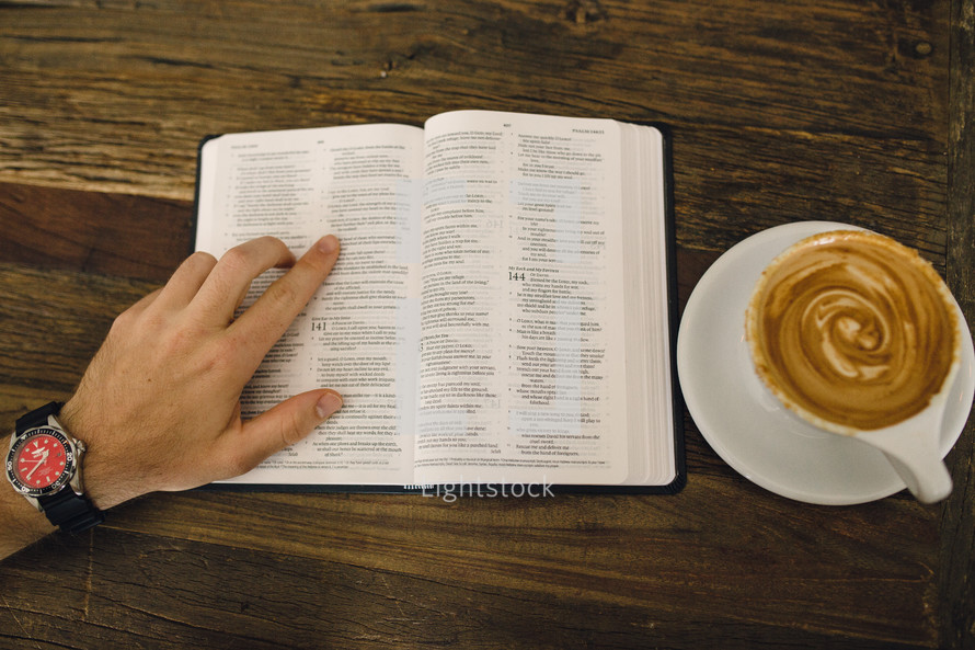 man reading a Bible and a cappuccino 