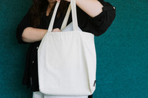 Woman in a black shirt pulling a laptop out of a canvas tote bag.