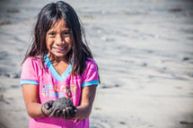 girl child holding a rock on a beach 