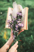 a woman holding a bouquet of flowers and a book 