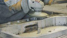 Clouse up of a worker's hands polishing a metal casting part using a grinder