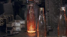 Glass bottles production. Glowing red hot glass bottles in a production facility
