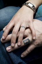 Tattoo Rings; married couple with cross and Trinity tattoos on ring fingers.