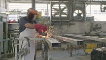 Slow motion of a worker using metal grinder with sparks flying at a metal shop