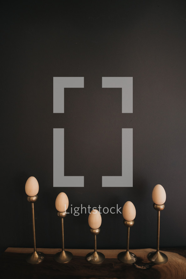 wooden eggs on candlesticks against a black background with copy space 