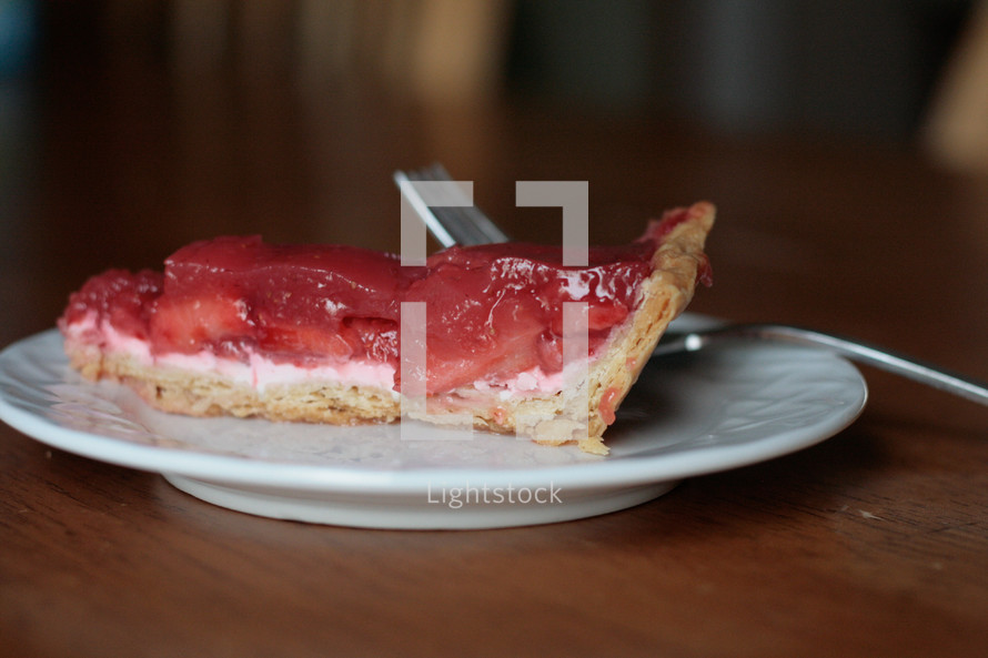 A piece of strawberry pie on a white plate.