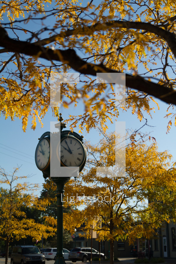 clock on a pole on a street corner 