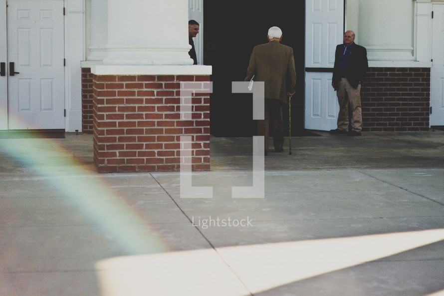 elderly man with a cane entering a church 