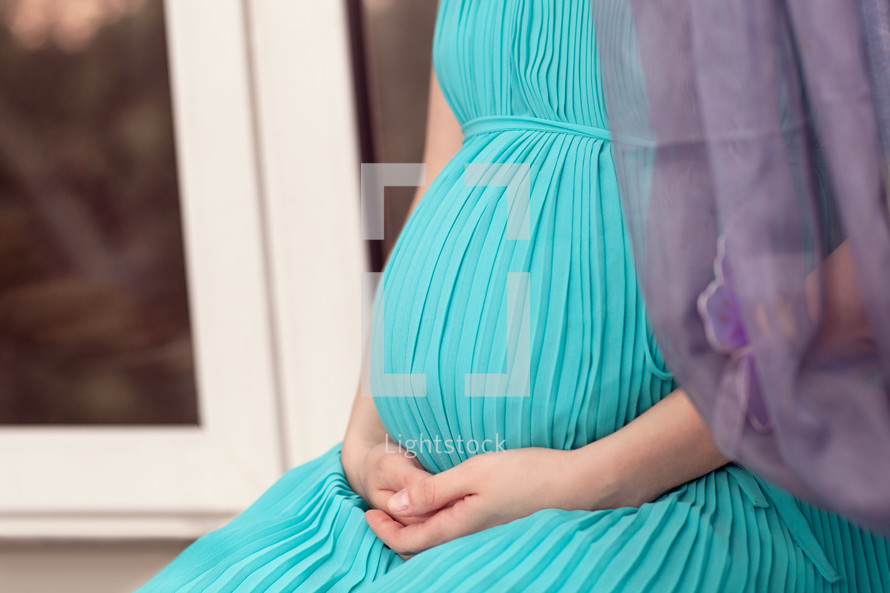 Pregnant woman on the window sill praying