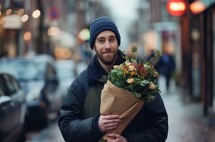 A bearded man in a winter hat warmly smiles, clutching a fresh bouquet of autumn flowers, evoking the feeling of a romantic gesture on a city street
