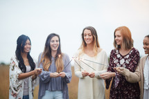 group of young women holding sparklers in a field  