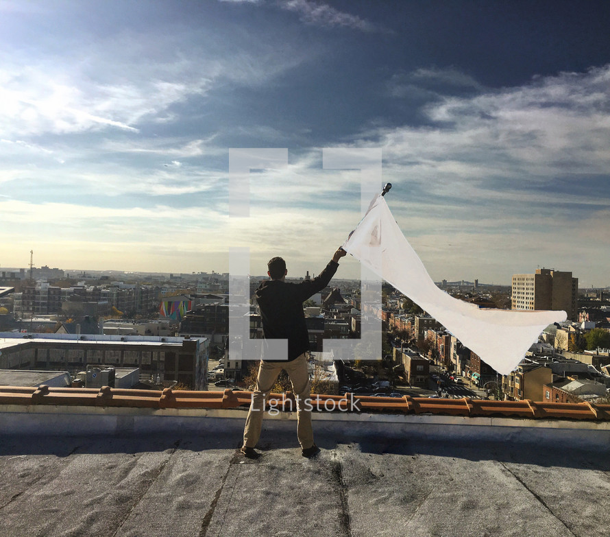 A man on a rooftop waving a white flag.
