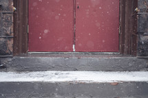 snow in front of red church doors 