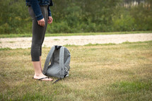 teen girl waiting at a bus stop next to her backpack 