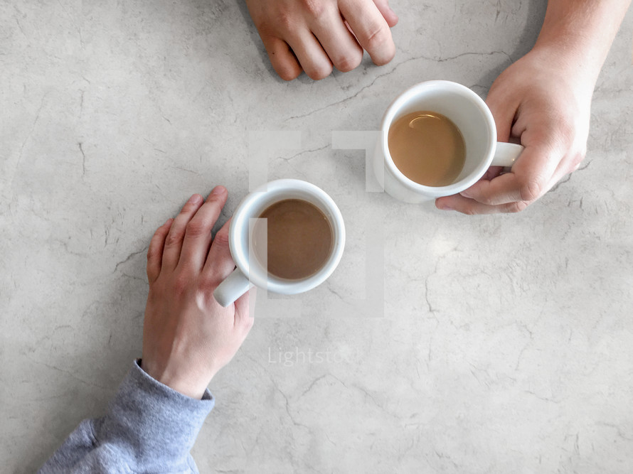 Friends sharing coffee abstract concept with cups and hands over white marble background shot from directly above