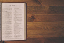Bible on a wooden table open to the book of Hosea.