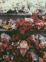 boy looking up to artificial flowers on a store shelf 
