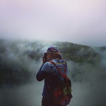 woman taking a picture on a foggy mountain 