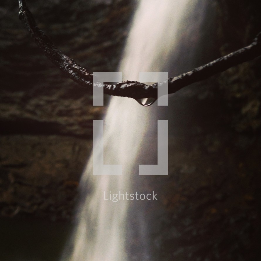 drop of water on a stick in front of a waterfall