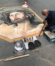 street artist painting Jesus on a sidewalk