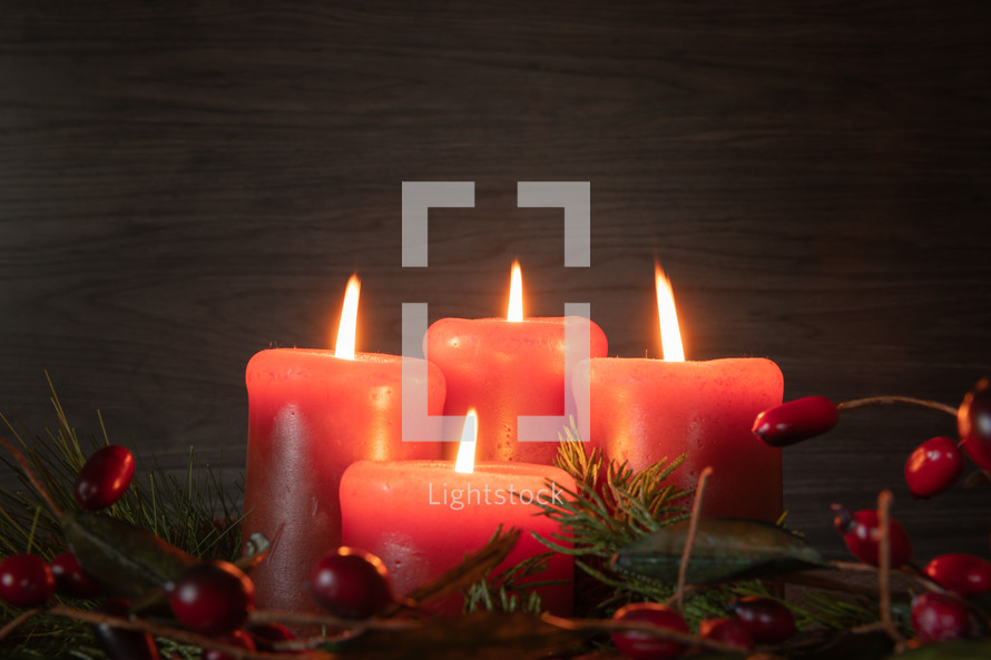 Lit advent candles in garland with berries