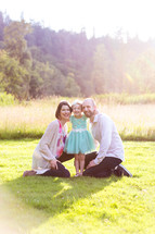 portrait of a family sitting in grass outdoors 