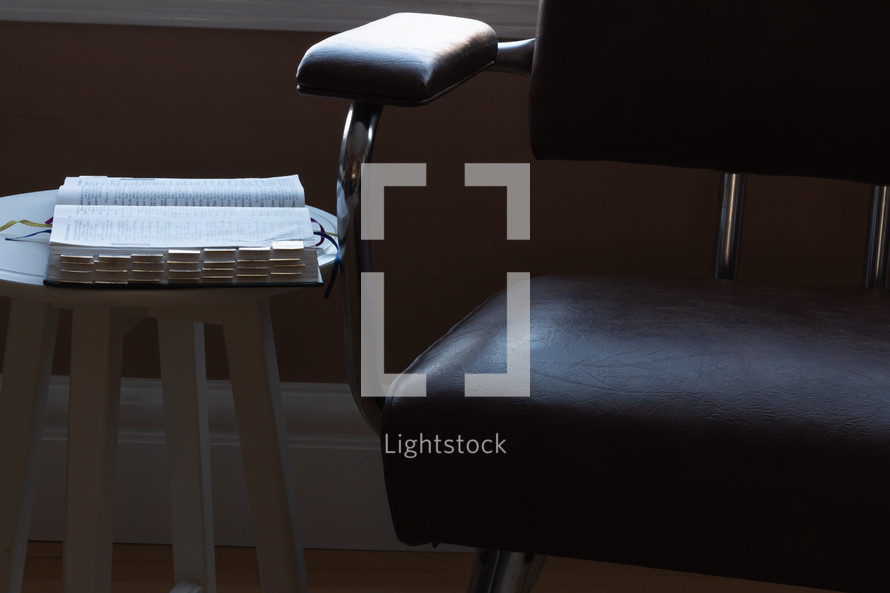 a Bible on a stool next to a chair 