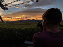 man taking a picture of the sunset 