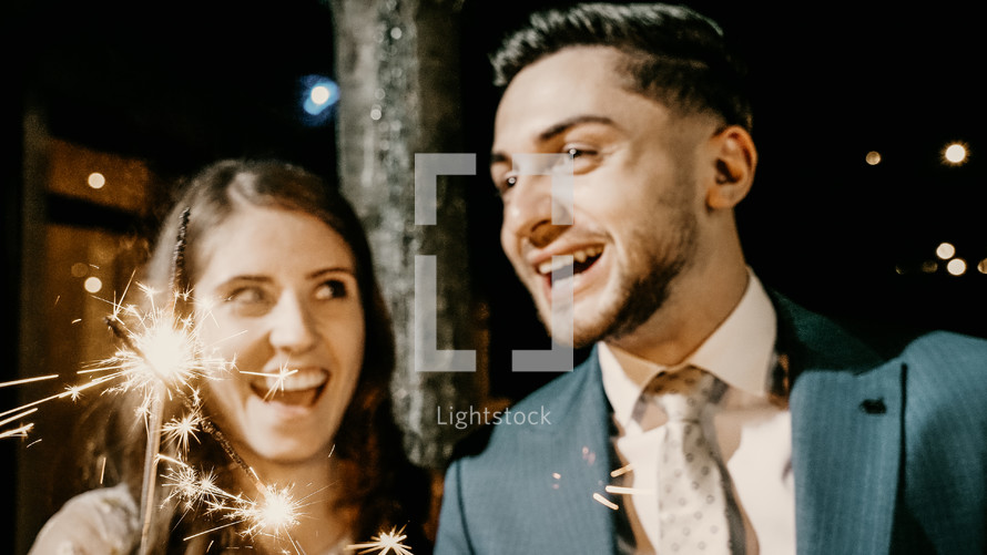 Man and woman smiling and holding a sparkler