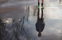 reflection of a boy child in a rain puddle 