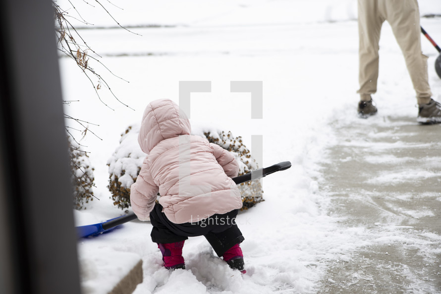 a little girl shoveling snow in winter 
