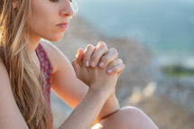 a young woman praying outdoors