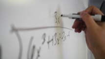 teacher writing equations on a whiteboard 