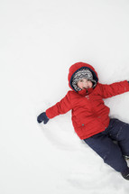 child making snow angels in the snow 