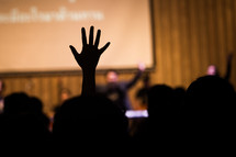 silhouettes of raised hands during a worship service, 