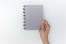 hand holding a silver notebook 