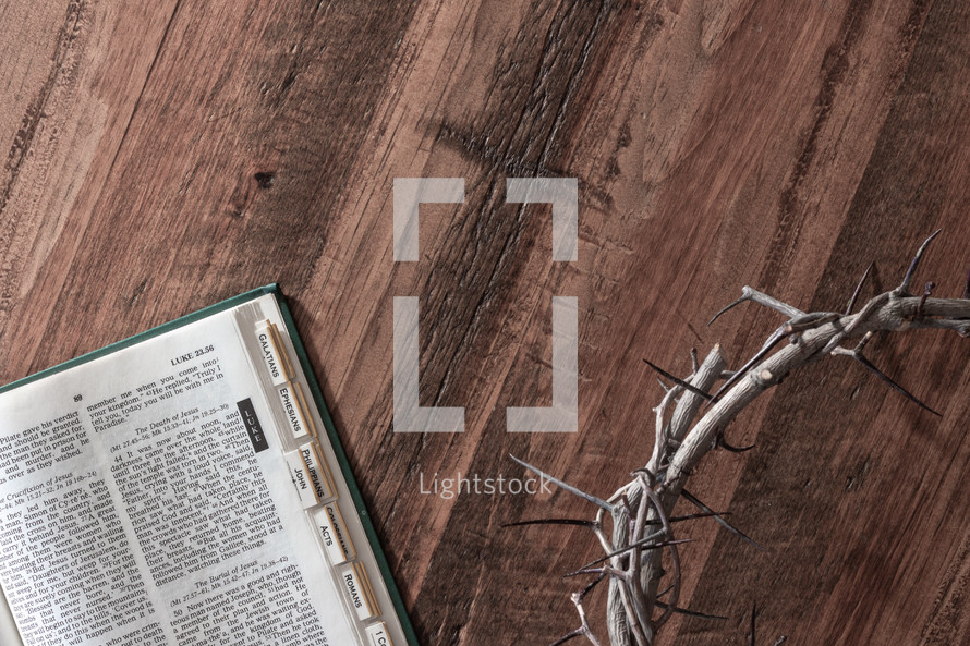 open Bible and crown of thorns on a wood background 