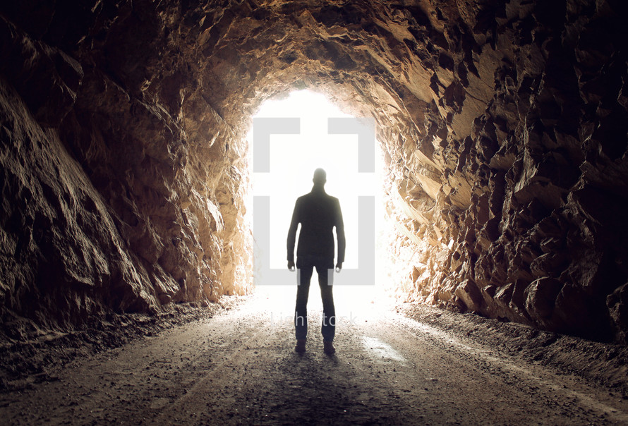 a man standing in a tunnel with light 