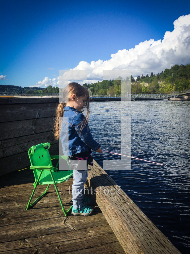 little girl fishing on a dock 