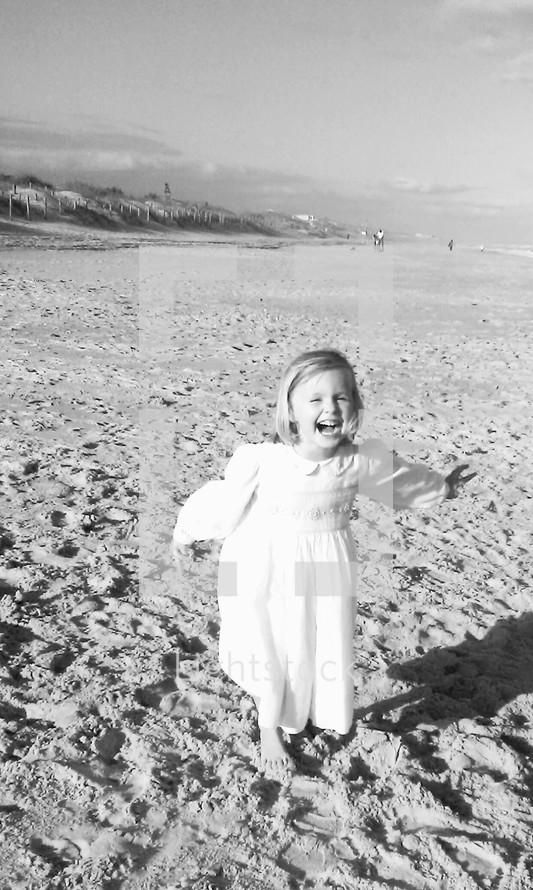 A happy little girl in a dress running on a beach carefree 