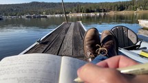 a man journaling on a dock 