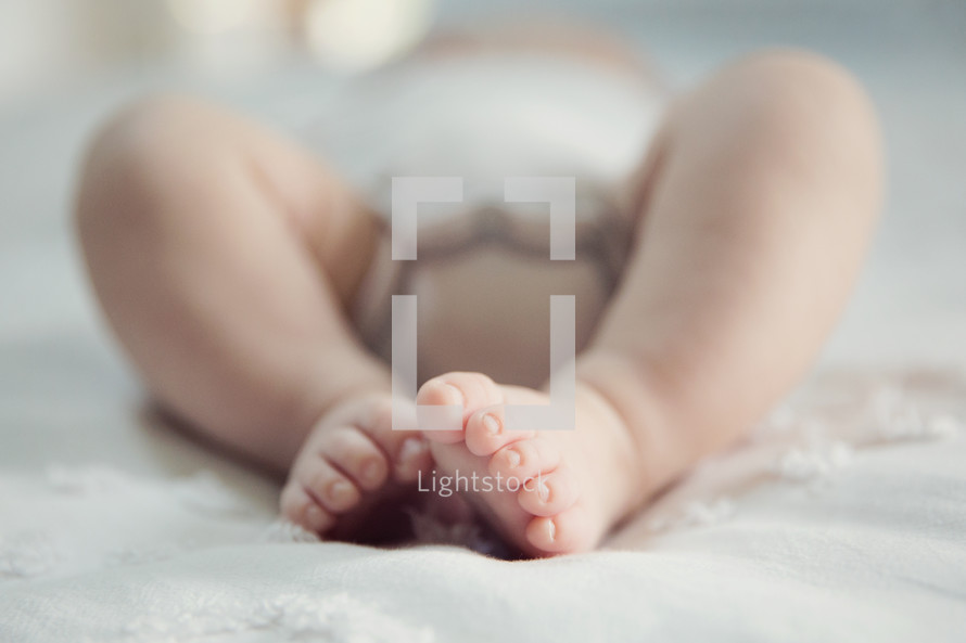 close up of infant feet on a bed.