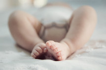 close up of infant feet on a bed.