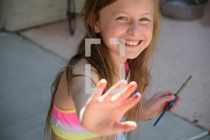 a little girl holding her hand out with paint on it 